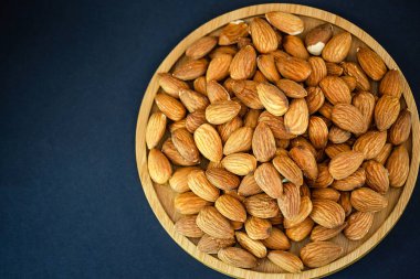 Badem fıstığı karışık tuz, siyah bir zemin üzerinde ahşap bir tabakta diyet yemeği ve protein yiyeceğidir..