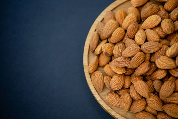 Almond Nut mixed salt is Protein food and healthy food for diet food in a wooden plate on a black background.