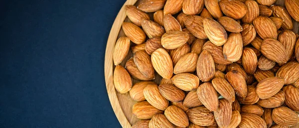 Almond Nut mixed salt is Protein food and healthy food for diet food in a wooden plate on a black background.