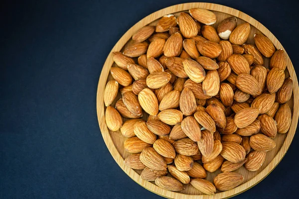 Almond Nut mixed salt is Protein food and healthy food for diet food in a wooden plate on a black background.