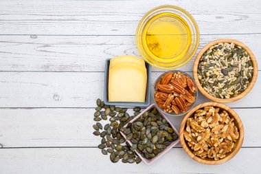 Grup fındıkları kaseye ve yumurtaya, zeytinyağına, peynirlere, ahşap masadaki sağlıklı gıdalara konur.