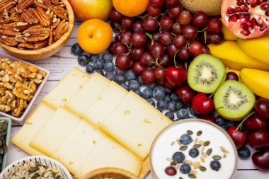 Kase üzerindeki fındıklar ve meyveler muz, ananas ve üzümler ahşap masa arkasındaki sağlıklı yiyecekler.