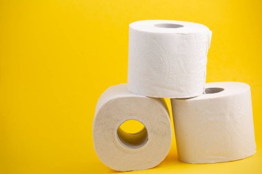 Banyolarda ya da mutfaklarda kullanılmak üzere büyük beyaz bir tuvalet kağıdı rulosu, sarı arka plandaki kirleri temizlemek için kullanılır.