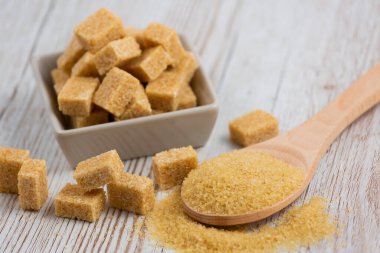 Kare bir fincanda esmer şeker ve ahşap bir masada tahta kaşık, sağlıklı şeker yemek veya tatlı pişirmek için kullanılır..