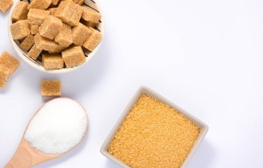 Yuvarlak bardakta kahverengi şeker ve beyaz zemin üzerinde ahşap kaşık, sağlıklı şeker yemek pişirmek ya da tatlılar için kullanılır..