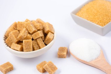 Yuvarlak bardakta kahverengi şeker ve beyaz zemin üzerinde ahşap kaşık, sağlıklı şeker yemek pişirmek ya da tatlılar için kullanılır..