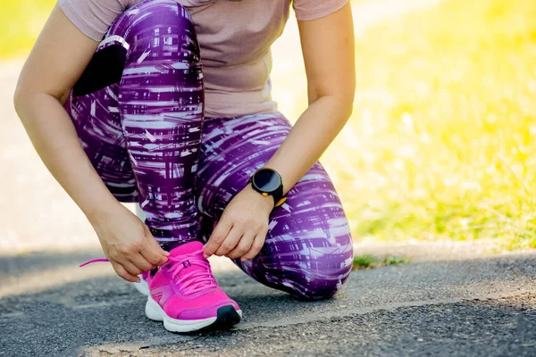 ランニングシューズカラーピンク 靴ひもを結ぶ女性 自然公園でのランニングやジョギングの準備をする女性スポーツランナーの閉鎖 — ストック写真