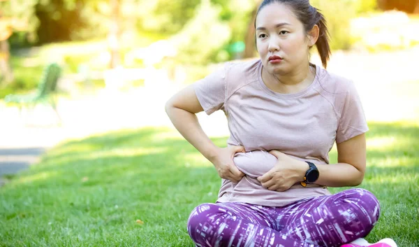 Young Asian woman has health problems and wants an exercise in the nature park, Exercise for health or, fresh air, or Oxygen in the green tree in the park in sunlight.