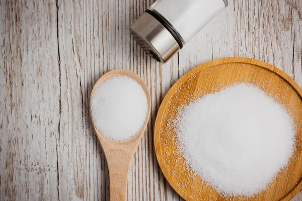 White sea salt for cooking food in Small glass bottles, wooden spoons, and trays on Old wooden table Background.
