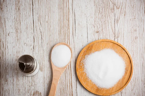 White sea salt for cooking food in Small glass bottles, wooden spoons, and trays on Old wooden table Background.