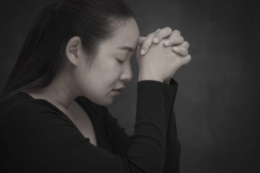 Asyalı kadın Tanrı 'ya dua ediyor ve ibadet ediyor. Dini inançlarda el ele tutuşuyor ve kilisede Hıristiyanlara ibadet ediyor. Ya da beyaz ve siyah arka planda genel yerlerde.
