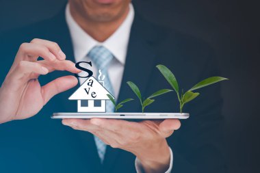 İş adamları siyah takım elbise giyer. İngiliz S harfini tutuyor, yani ev simgesini kurtarıyor ve tablet ekranını siyah bir arkaplanda bırakıyor.