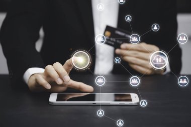 İş adamı grafik simgesini seçer ve bilgisayarla veya akıllı fonla modern bir kredi kartı kullanır. İnternet üzerinden alışveriş yapar ve sipariş alışverişini internetten satın alır..