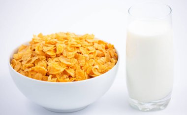 Doğal mısır gevreği kahvaltı gevreği fincanda ve süt sağlıklı bir kahvaltıdır. Beyaz arka planda her gün vücudunuz için iyidir..