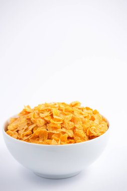 Doğal mısır gevreği kahvaltı gevreği fincanda ve süt sağlıklı bir kahvaltıdır. Beyaz arka planda her gün vücudunuz için iyidir..