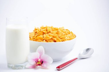 Doğal mısır gevreği kahvaltı gevreği fincanda ve süt sağlıklı bir kahvaltıdır. Beyaz arka planda her gün vücudunuz için iyidir..