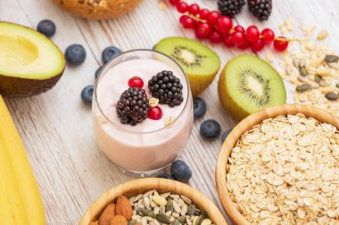 Ekmek, kepekli ve fındıklı grup meyveli kahvaltı, kirazlı yoğurt, muz, ahşap masada avokado. Sağlık ve Diyet Kahvaltısı konsepti