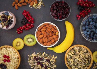 Ekmek, kepekli ve fındıklı grup meyveli kahvaltı, kirazlı yoğurt, muz, ahşap masada avokado. Sağlık ve Diyet Kahvaltısı konsepti