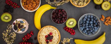 Ekmek, kepekli ve fındıklı grup meyveli kahvaltı, kirazlı yoğurt, muz, ahşap masada avokado. Sağlık ve Diyet Kahvaltısı konsepti