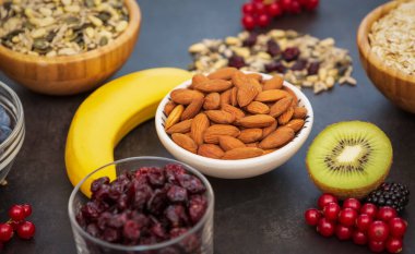 Ekmek, kepekli ve fındıklı grup meyveli kahvaltı, kirazlı yoğurt, muz, ahşap masada avokado. Sağlık ve Diyet Kahvaltısı konsepti