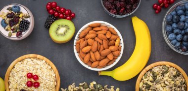 Ekmek, kepekli ve fındıklı grup meyveli kahvaltı, kirazlı yoğurt, muz, ahşap masada avokado. Sağlık ve Diyet Kahvaltısı konsepti