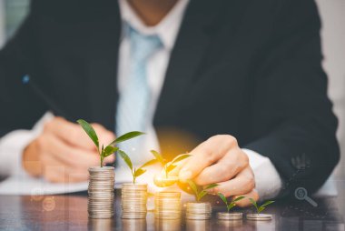 İşadamı madeni paralara hat bağlantısı ile dokunur ve madeni paralar ahşap masaya istiflenir, fikirleri ve yatırım bütçesini saklar, para tasarrufu kavramı yaratıcılığı kavramı, yer kopyalama