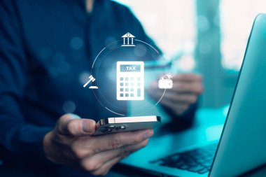 Businessman using a laptop to manage digital tax processes. Conceptual icons for e-commerce tax, corporate tax, and financial management overlayed on a virtual interface.