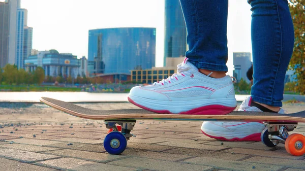 Genç kız sonbahar parkında bir kaykay üzerinde sürmek.