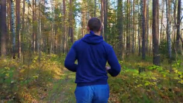 Молодой человек бегает по осеннему лесу . — стоковое видео