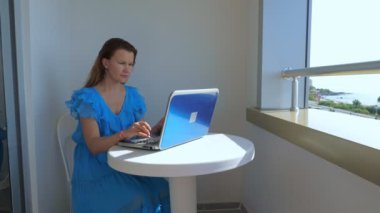 Kız otelin balkonunda dizüstü bilgisayarda çalışıyor..