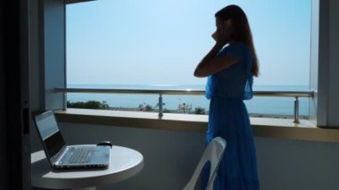 Otel odasının balkonunda cep telefonuyla konuşan serbest çalışan kız..