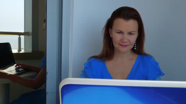 Flickan arbetar på en bärbar dator på balkongen på hotellet. — Stockvideo