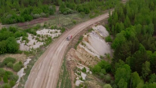 Un camion transportant du minerai longe une forêt estivale