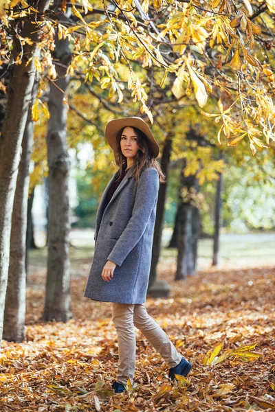 Portret van mooie jonge vrouw lopen buiten in herfst park in gezellige jas en hoed. Warm zonnig weer. Val concept. — Stockfoto