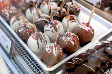 Ev yapımı karamel elmalar ile fındık ve beyaz ve sütlü çikolata pazarında Viyana'da tepsi üzerinde Çiseleme.