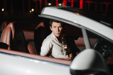 Beyaz Cabriolet yakışıklı bir adam portresi. Gece hayatı. Lüks araba takım elbiseli işadamı.