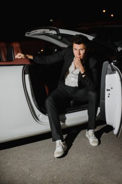 Beyaz Cabriolet yakışıklı bir adam portresi. Gece hayatı. Lüks araba takım elbiseli işadamı.