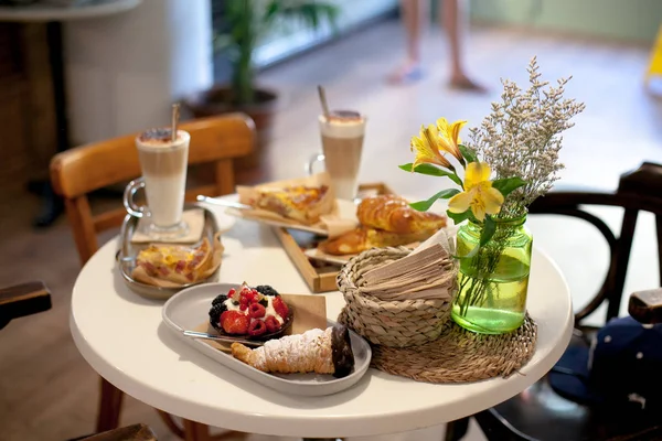 delicious breakfast for two at the luxury hotel with fresh hot pie, tart with berry jam, croissant and coffee cappuccino on light table. Cafe brunch