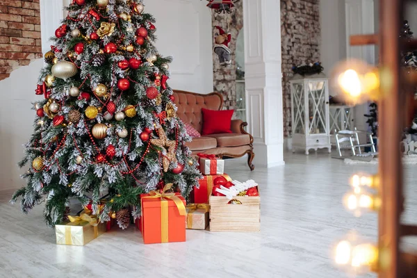 圣诞和新年装饰室内 白墙前装饰着红色的礼物 圣诞树和经典的棕色沙发 — 图库照片