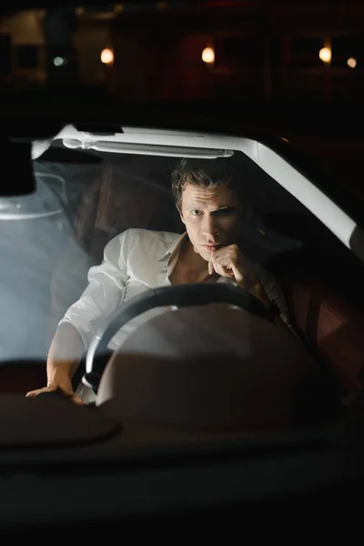 Yakışıklı moda adam araba cabriolet sürüş. Lüks. Gece hayatı. Trafik ışıkları arkasında. Telifsiz Stok Imajlar