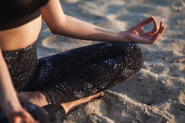 Yakın çekim anonim el kadın içinde Lotus pozisyonu, kum Beach