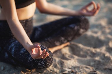 Yakın çekim anonim el kadın içinde Lotus pozisyonu, kum Beach
