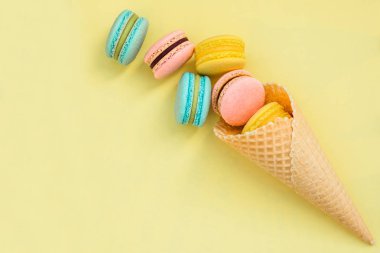 Gözleme koni ile renkli macaron veya sarı pastel arka plan üstten görünüm üzerinde acıbadem kurabiyesi. Düz yatıyordu kompozisyon