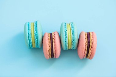 Bir yığın macaroons mavi pastel renkli, üstten görünüm üzerinde çeşitli lezzet bisküvi. Macarons yatıyordu yelpazesi paylamak