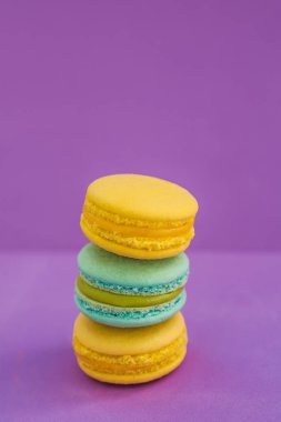 Bademli kurabiye bisküvi menekşe mor arka plan, üstten görünüm üzerinde farklı tatlar yığını. Renkli macarons yatıyordu yelpazesi paylamak