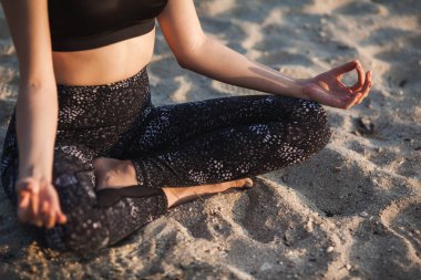 Yakın çekim anonim el kadın içinde Lotus pozisyonu, kum Beach