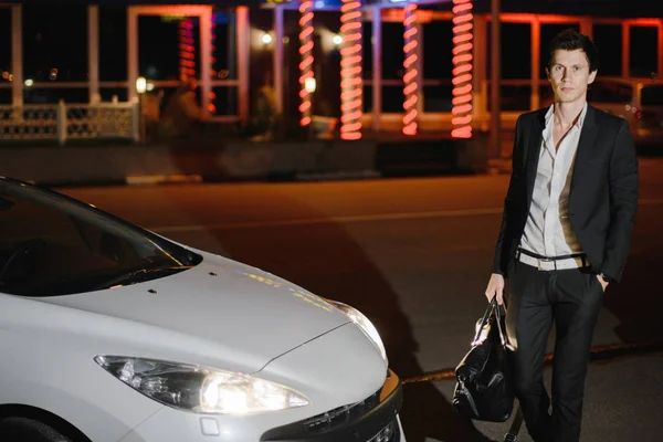 그의 흰색 쿠 페 형 자동차 옆에 서 있는 세련 된 젊은 남자. 밤문화입니다. 럭셔리 자동차에 맞게 사업 — 스톡 사진