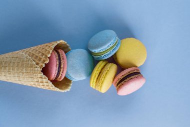 Dondurma waffle koni ile renkli macaron veya mavi pastel renkli üstten görünüm üzerinde acıbadem kurabiyesi. Renkli şeker renkleri. Tatlı, tatlı, yaz konsepti. Üstten görünüm. Düz yatıyordu kompozisyon.