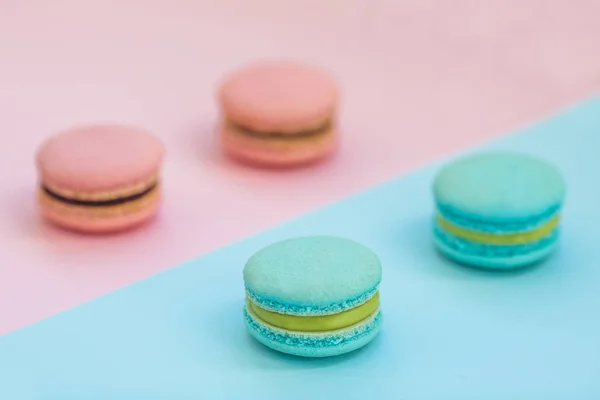 Zoete kleurrijke Frans macaroon koekjes op roze en blauwe pastel achtergrond, bovenaanzicht. Flay lag selectie van macarons. — Stockfoto