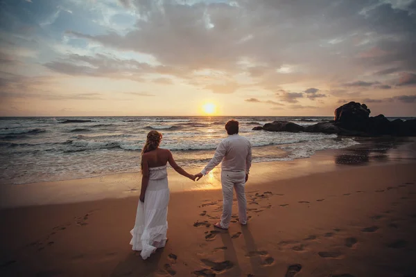 Young couple enjoying the sunset on the beach on background colorful sky and reflection in water.wedding Travel Lifestyle Concept. Honeymoon